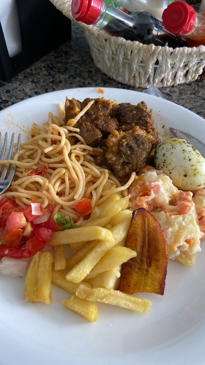 a white plate topped with pasta, meat and veggies next to a fork