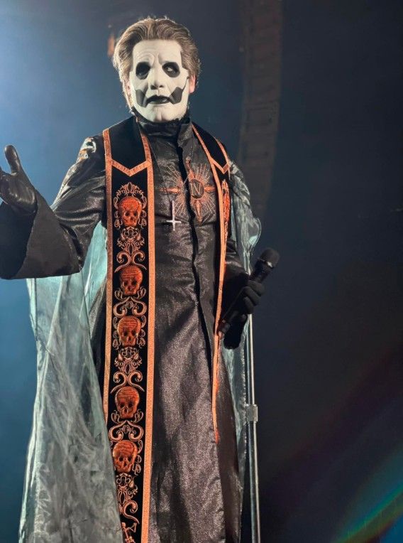 a man in a costume on stage with his hands out and one hand up to the side