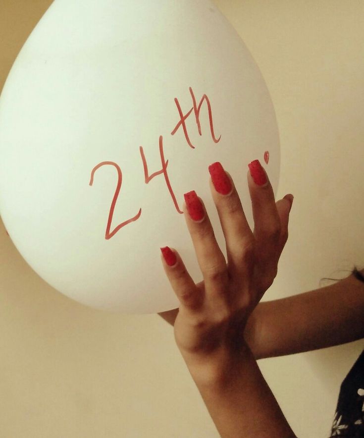 a woman holding up a large white balloon with the number twenty seven written on it