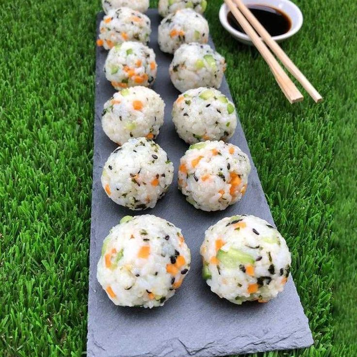 several balls of sushi on a blue mat with chopsticks next to it