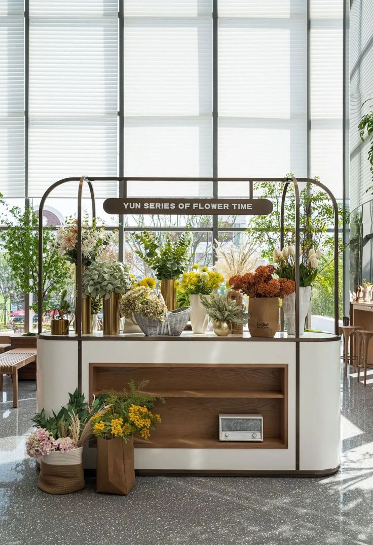 a flower shop with lots of potted plants and flowers on the counter in front of it