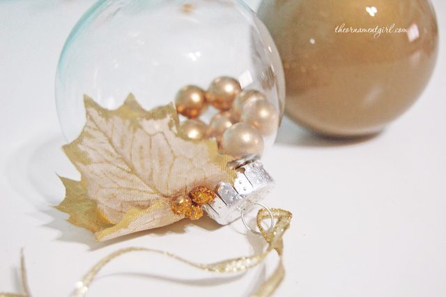 a glass ornament with a leaf on it and some beads in the bottom