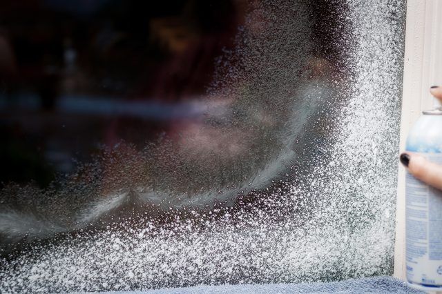 a person holding a can of soda in front of a window with snow falling on it