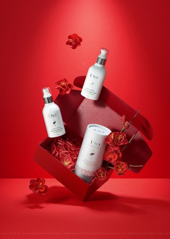 a red box with three bottles of body lotion in it and flowers on the side