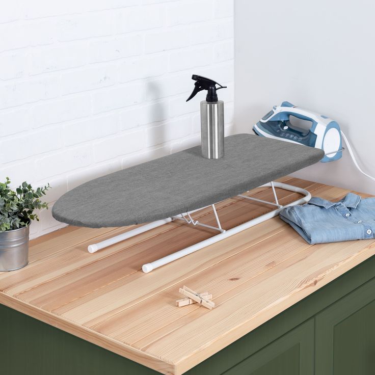 an ironing board on top of a wooden counter next to a potted plant