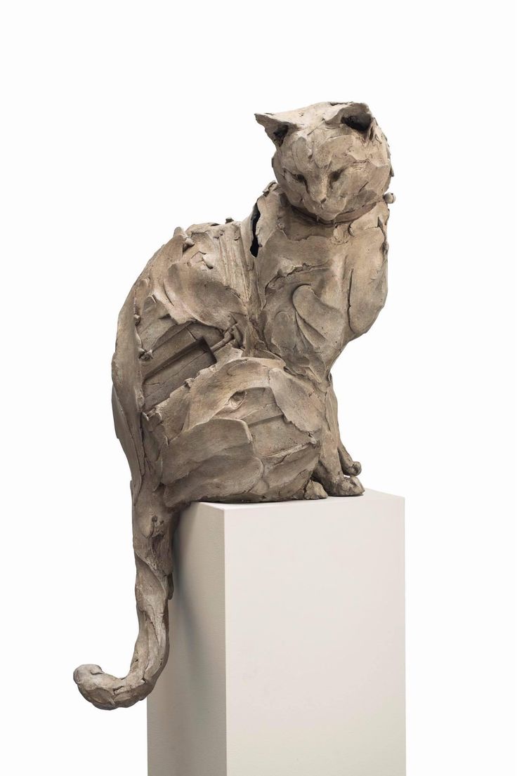 a sculpture of a cat sitting on top of a white block in front of a white background