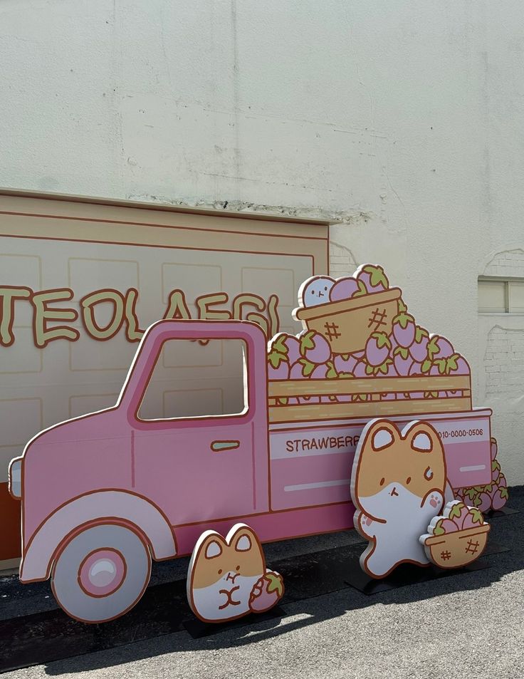 a pink truck is parked in front of a wall with some decorations on the side