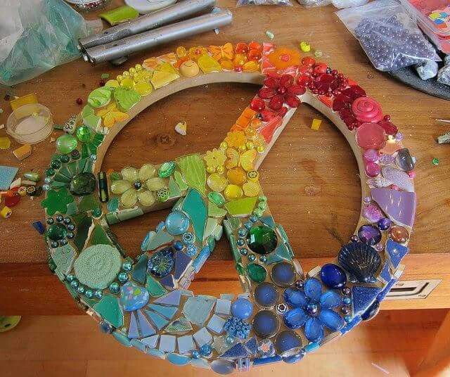 a peace sign made out of glass beads and other items sitting on a wooden table