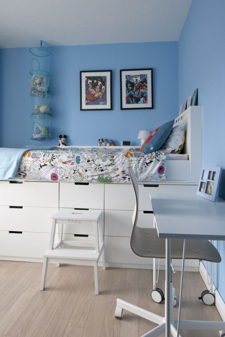 a bedroom with blue walls and white furniture