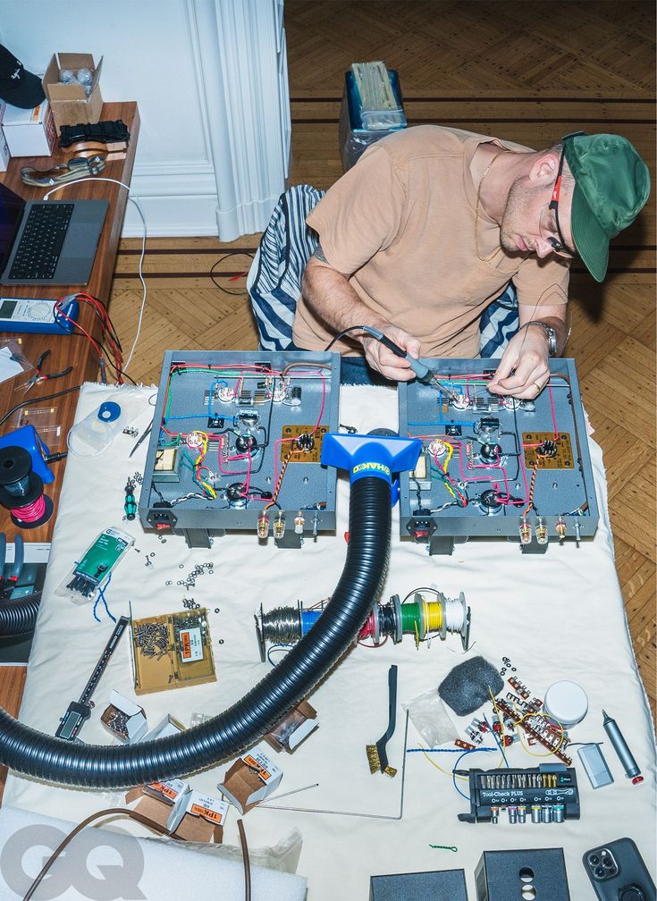 a man is working on an electronic device with many wires and components around him,