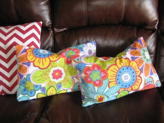 three decorative pillows on a brown leather couch