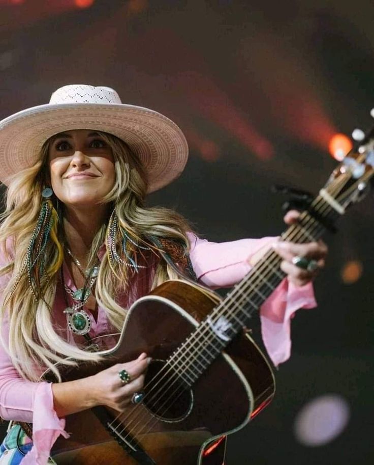 a woman wearing a cowboy hat and holding a guitar