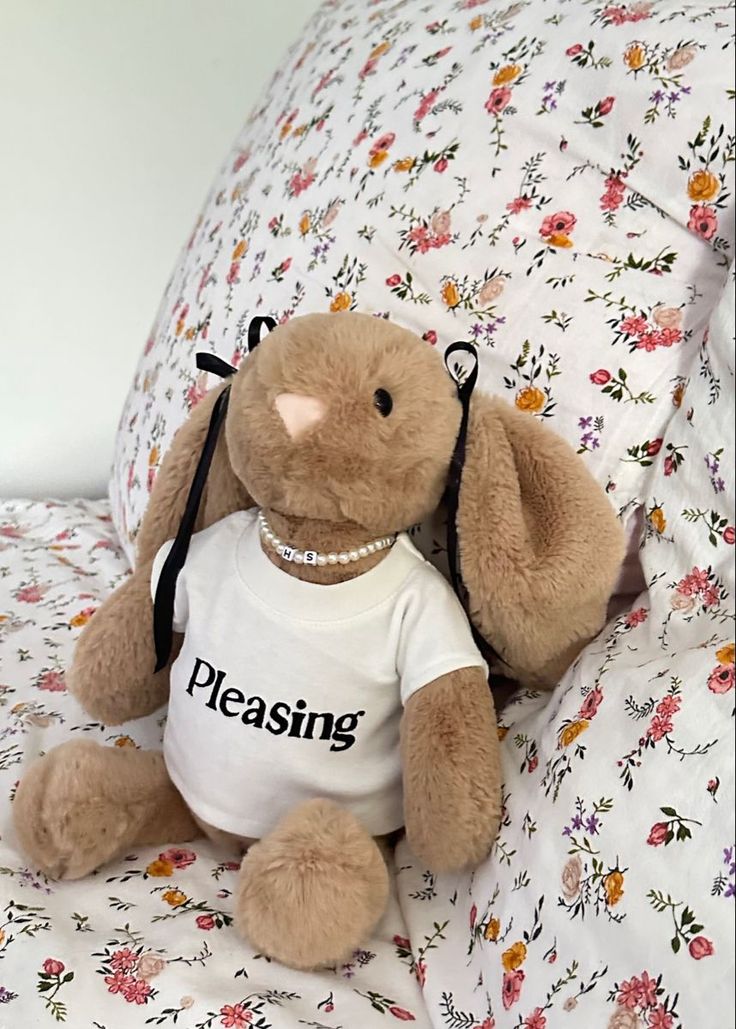 a stuffed animal sitting on top of a bed next to a flowered comforter