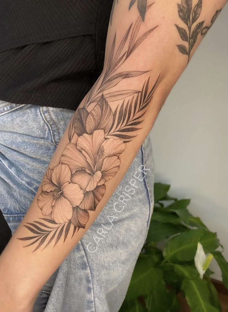 a woman's arm with flowers and leaves tattooed on the left side of her arm