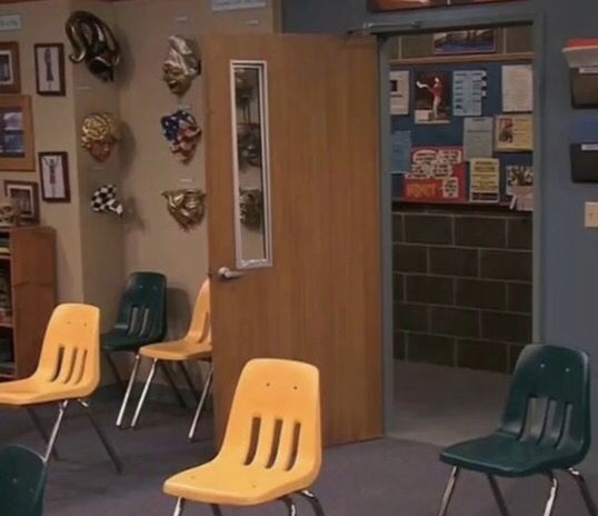 several school chairs are lined up in a room with pictures on the wall and posters on the walls