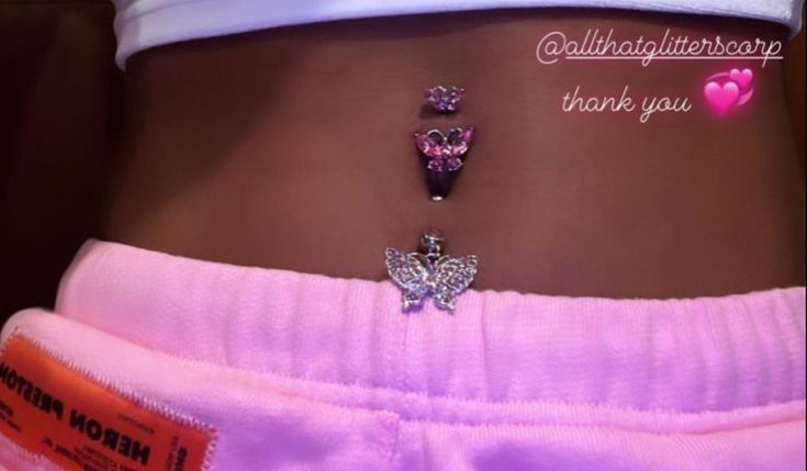 a woman's stomach with two butterfly charms attached to her belly and the words hello kitty written on it