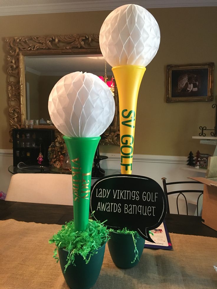 two green vases with white paper balls in them sitting on a dining room table