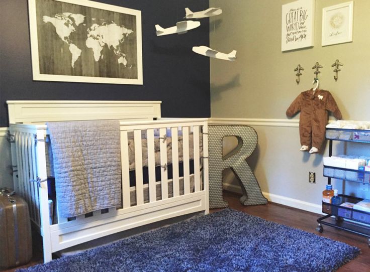 a baby's room with a crib, rug and wall hangings on the walls