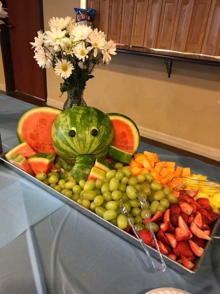 a watermelon shaped as a frog sitting in front of a platter of fruit