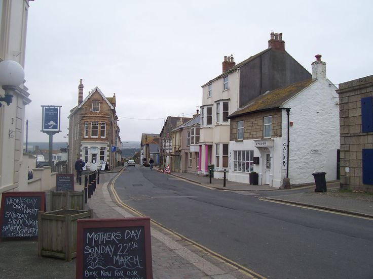 an empty street with some buildings on both sides and chalkboard signs in the foreground