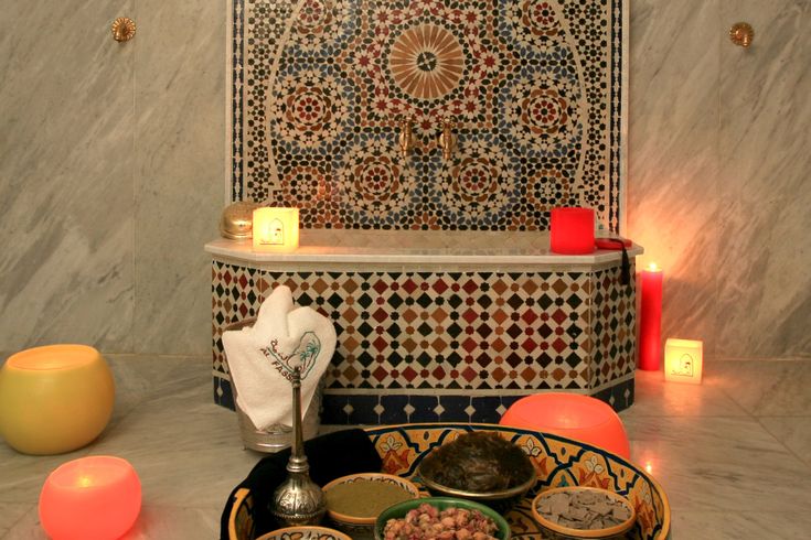 candles are lit in front of an ornate tiled wall and bowl with food on it