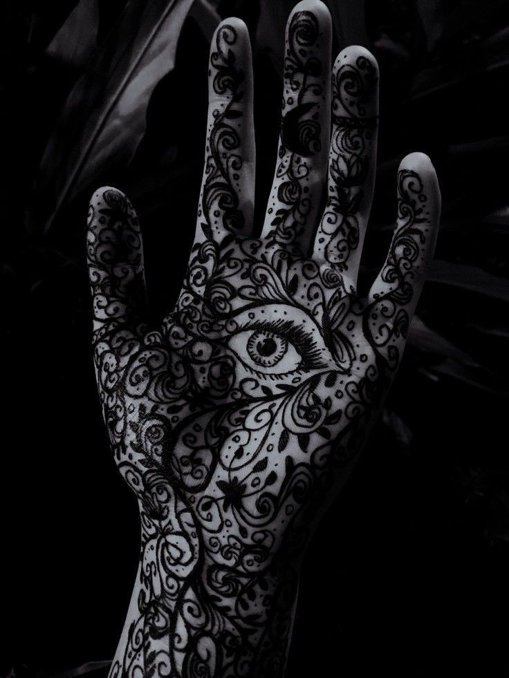 a person's hand painted with black and white hennap, which has an all seeing eye on it