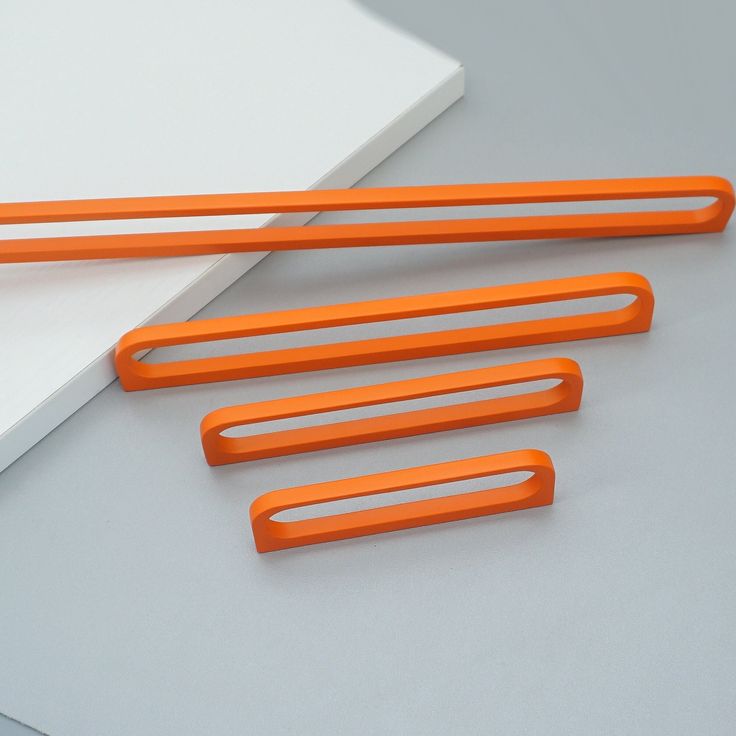 four orange plastic handles on a white surface