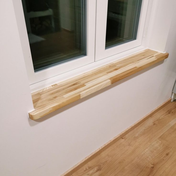 a wooden shelf sitting in front of two windows