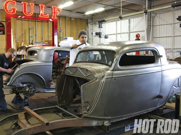 two men working on an old car in a garage