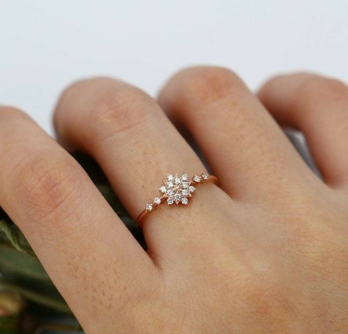 a woman's hand with a ring on it that has three small flowers in the middle