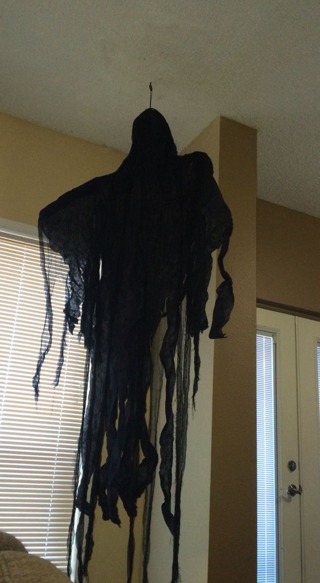 a black cloth hanging from the ceiling next to a bed in a room with beige walls