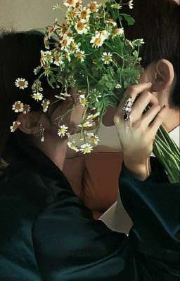 a woman covering her face with a bouquet of daisies in front of her face