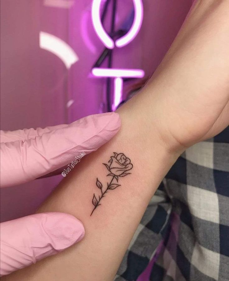 a woman's arm with a small rose tattoo on the left side of her wrist