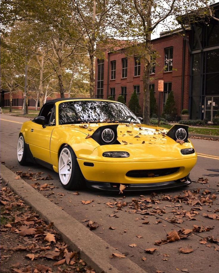 a yellow sports car parked on the side of the road in front of a brick building