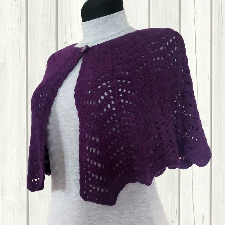 a woman wearing a purple crocheted shawl on top of a mannequin