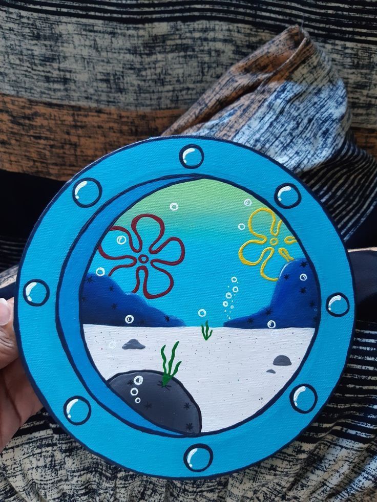 a person holding up a painted plate with an octopus and seaweed design on it