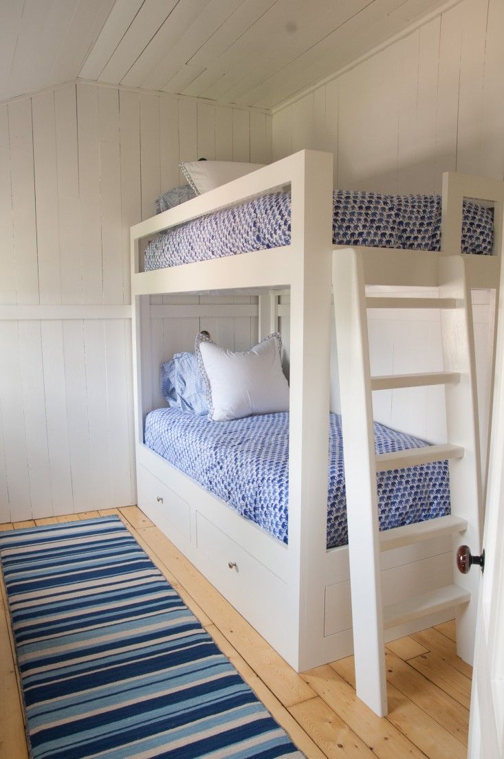 a bunk bed with blue and white bedspread in a room next to a rug