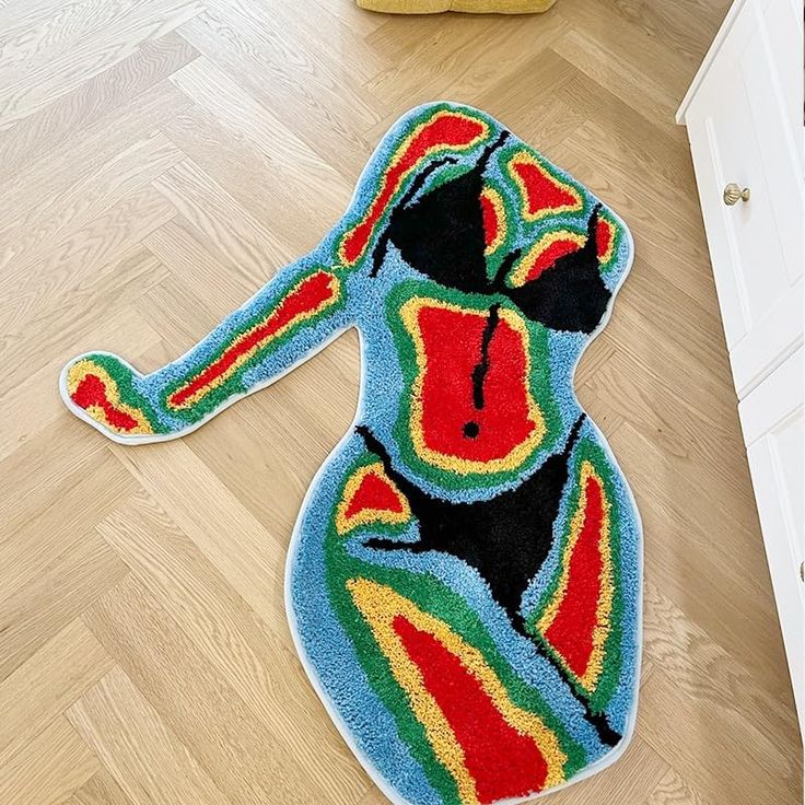 a multicolored dog shaped rug is on the floor next to a white cabinet