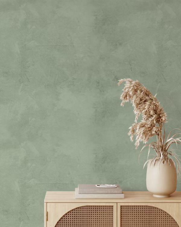 a white vase sitting on top of a wooden cabinet next to a green painted wall