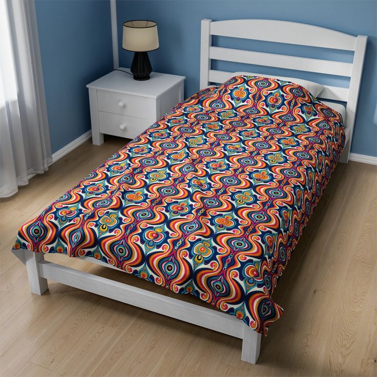 a bed with a colorful bedspread on top of it next to a night stand