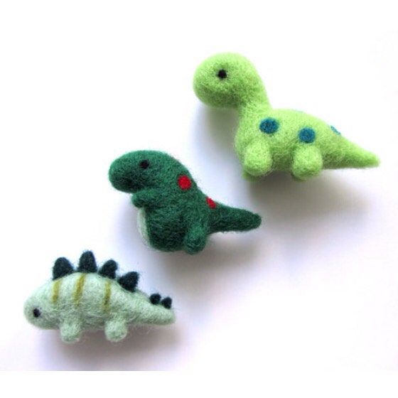 three small stuffed dinosaurs sitting next to each other