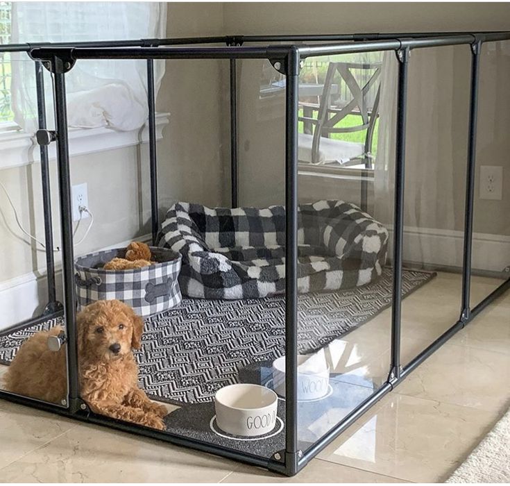 a dog laying on the floor in front of a cage with its food and water bowl