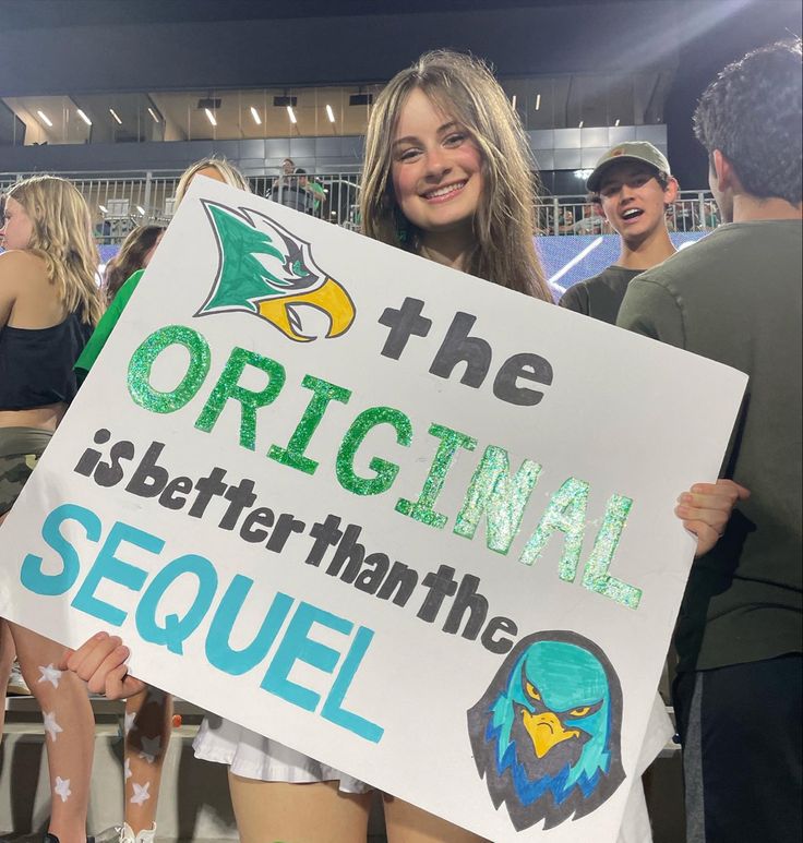 a girl holding a sign that says the original is better than the sequel