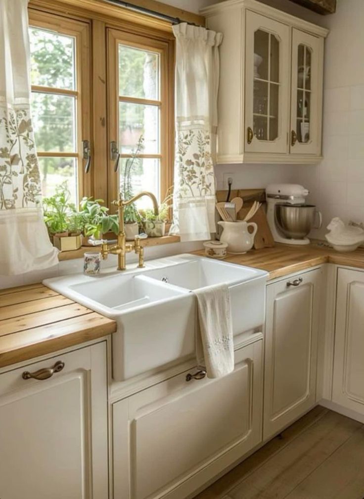 a kitchen with white cabinets and wooden counter tops, along with a window above the sink