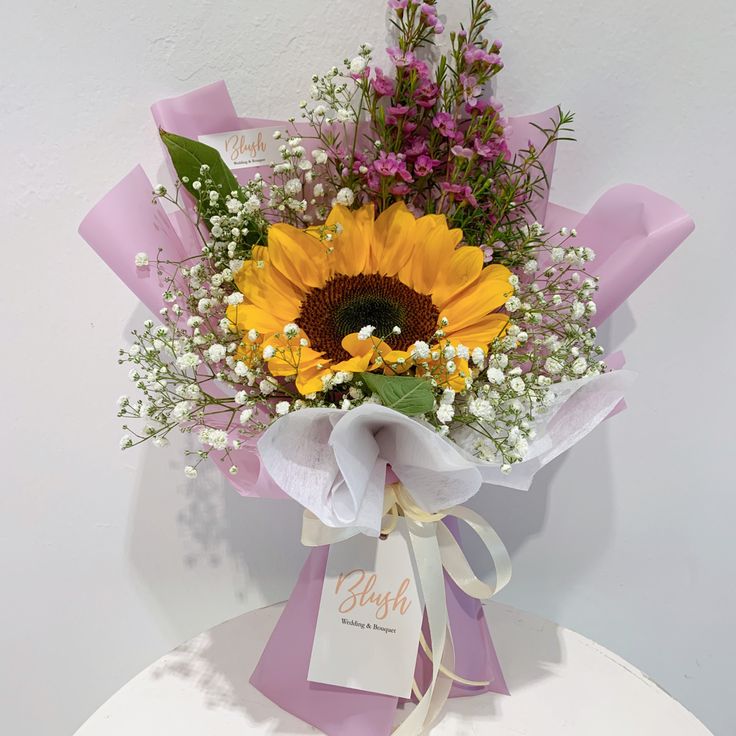 a bouquet of sunflowers and baby's breath tied to a white box