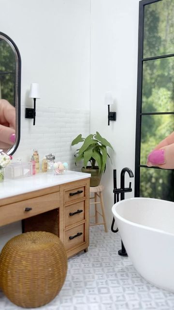 a woman's hand with pink nail polish is reflected in the mirror next to a bathtub