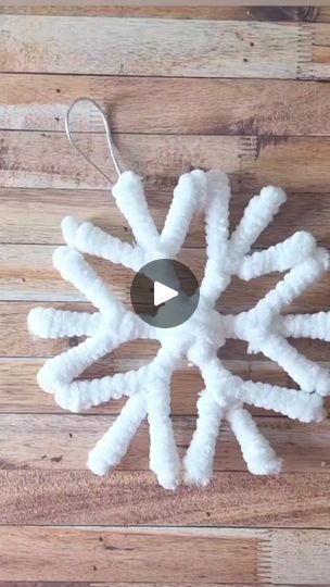 a white snowflake ornament hanging on a wooden floor with a video