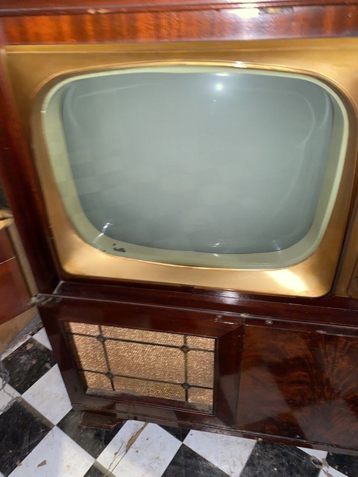 an old fashioned television sitting on top of a wooden stand in front of a black and white checkered floor