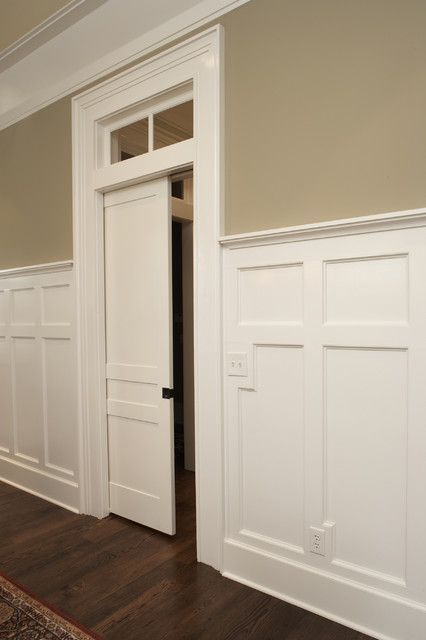 an empty room with white paneling on the walls and wood floors, along with a rug