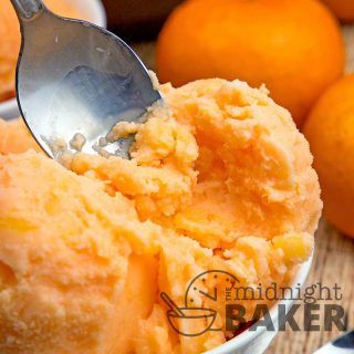 an ice cream scooping out of a bowl with oranges in the background